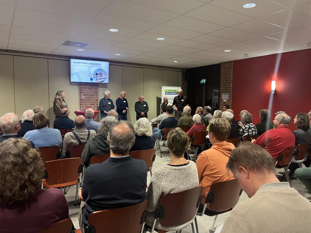 Een zaal vol mensen in De Koningshof te Leusden die luisteren naar een presentatie van het buurtteam van de buurt Langenbeek