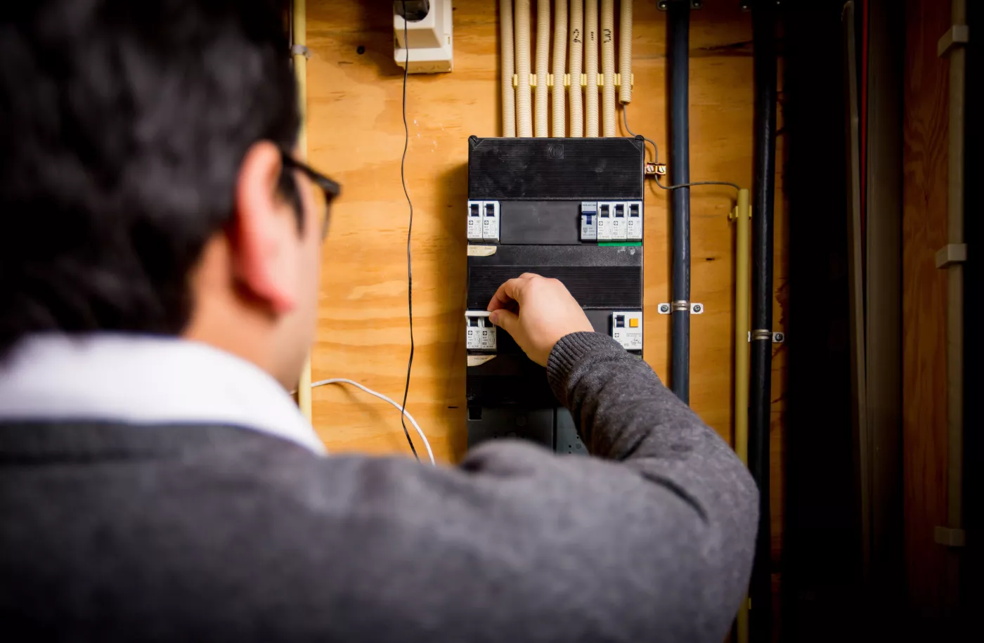 Een man zet een van de schakelaars om in de meterkast
