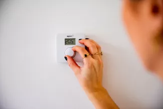 Een persoon draait de thermostaat in huis op 20 graden