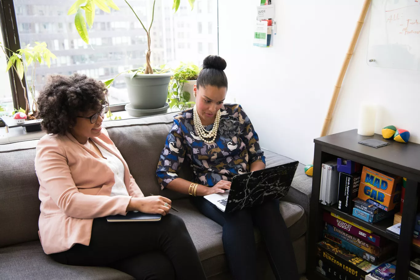 Twee vrouwen zijn samen in gesprek op de bank. Eentje heeft een laptop.