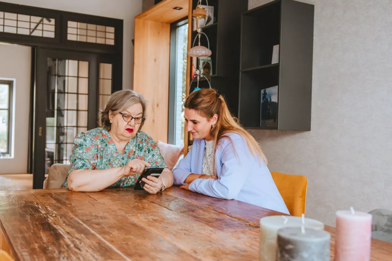 2 vrouwen aan tafel kijken op een telefoon