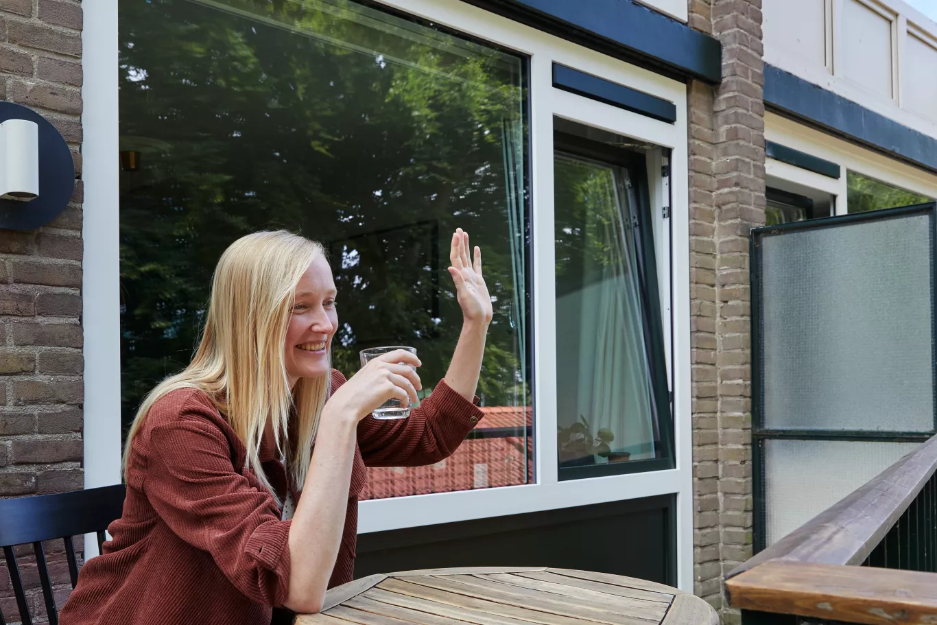 Inwoner zit op haar balkon en zwaait